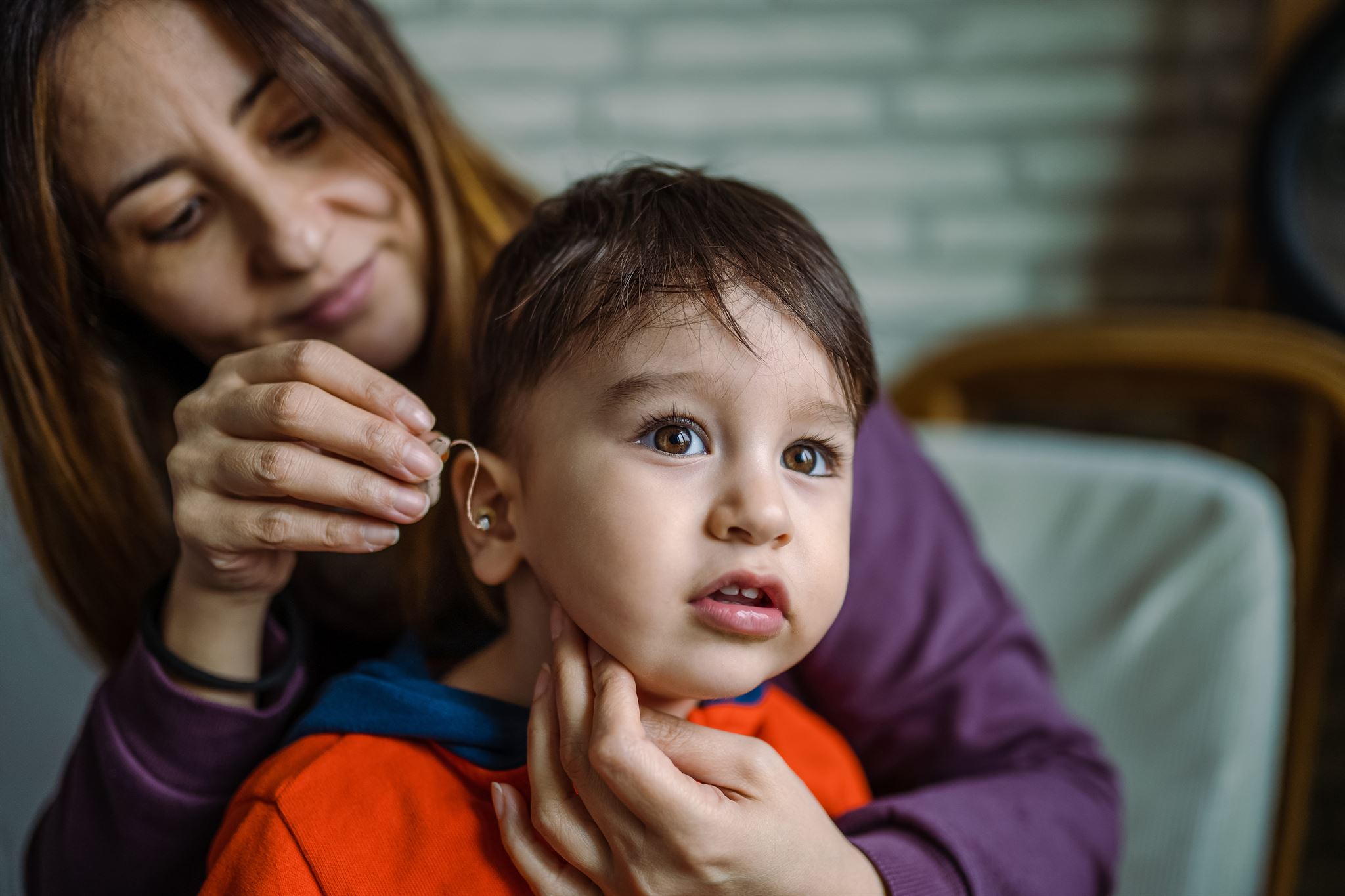 Woman-adjusting-hearing-aid-on-child